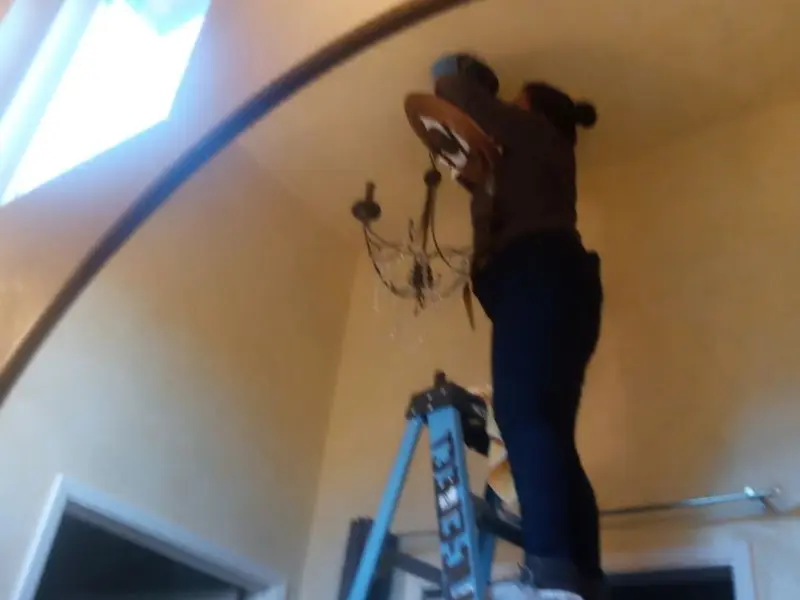 Electrician installing a chandelier in a Normandy residence